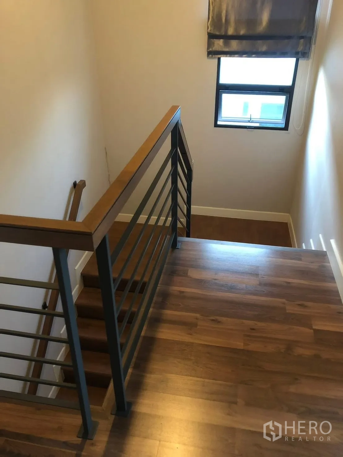 Detached House for rent in Prawet, Bangkok - Staircase with wooden treads and metal railing beside a window with a shade.