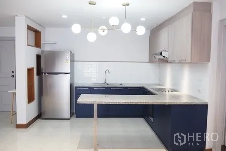 Condominium for rent in Pathum Wan, Bangkok - Modern L-shaped kitchen with pendant lights, fridge and white subway tile backsplash.