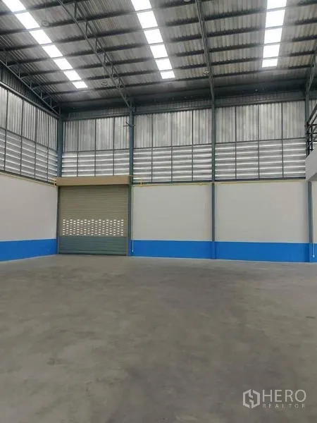 Warehouse for rent in Bang Phli, Samut Prakan - Panoramic view of multiple warehouse units with a landscaped pond and trees.