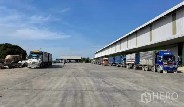 โรงงาน ให้เช่าในSai Noi, Nonthaburi - ลานคอนกรีตกว้าง รถบรรทุกหลายคันจอดที่ช่องโหลดดิ้งมีหลังคาของคลังสินค้า