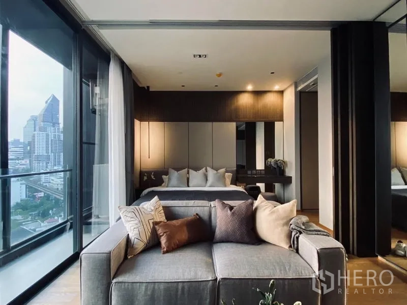 Condominium for sale - Bedroom behind the sofa with paneled headboard, mirrors and city outlook.