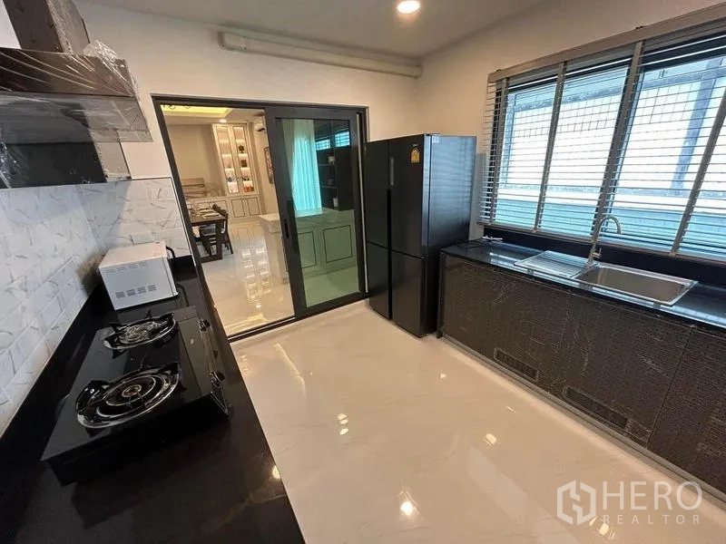 Detached House for rent in Bang Phli, Samut Prakan - Separate kitchen with gas hobs, black countertops and large window.