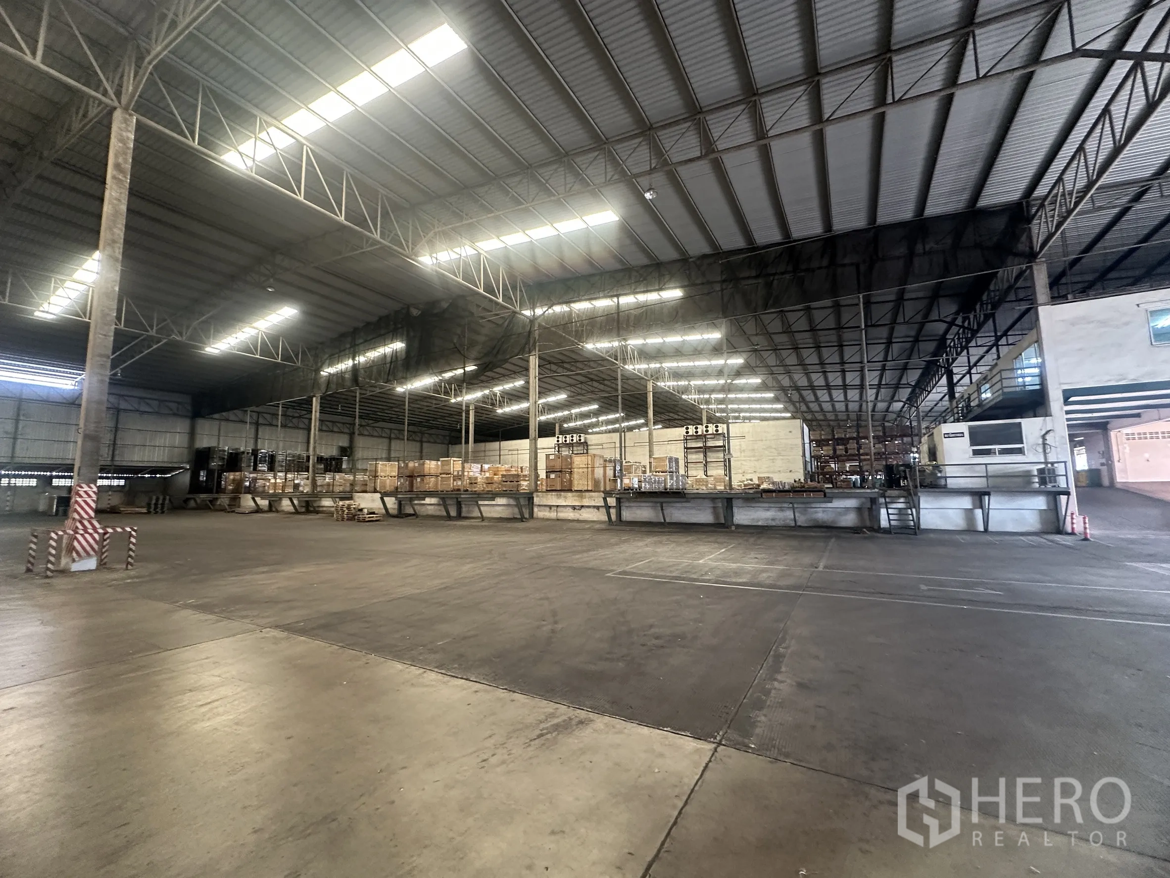 Warehouse for rent in Bang Pa-in, Phra Nakhon Si Ayutthaya - Spacious warehouse interior with steel truss roof, raised dock platforms, and pallets.