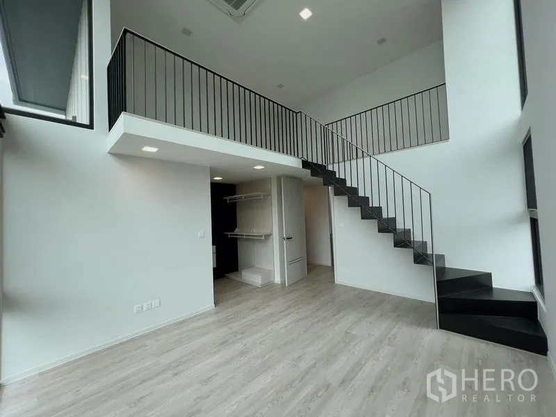Detached House for rent or sale in Saphan Sung, Bangkok - Double-height room with black staircase leading to a mezzanine loft.
