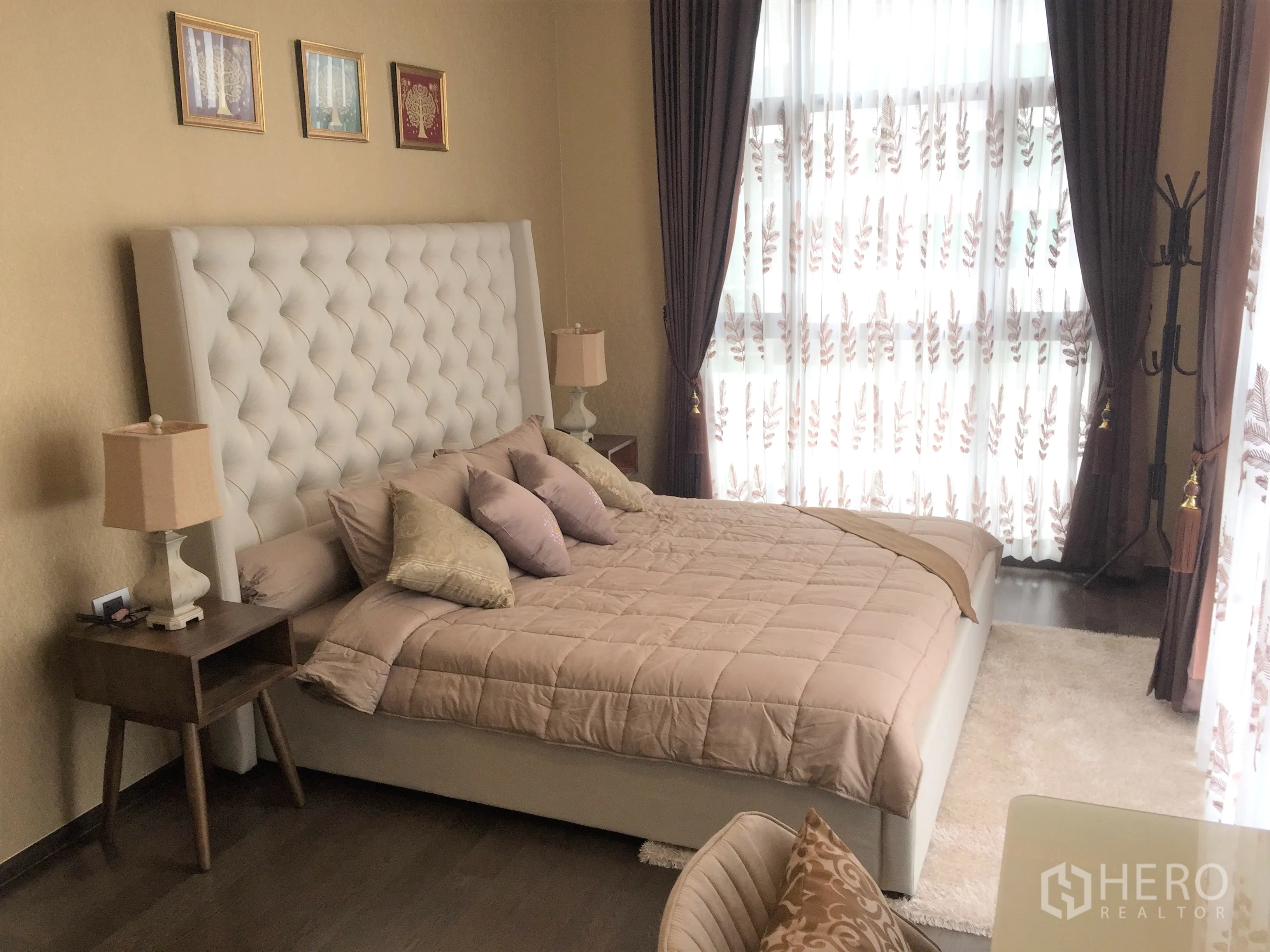 Condominium for rent in Watthana, Bangkok - Cozy bedroom with tufted headboard bed, bedside tables, thick drapes, and natural light from large windows.