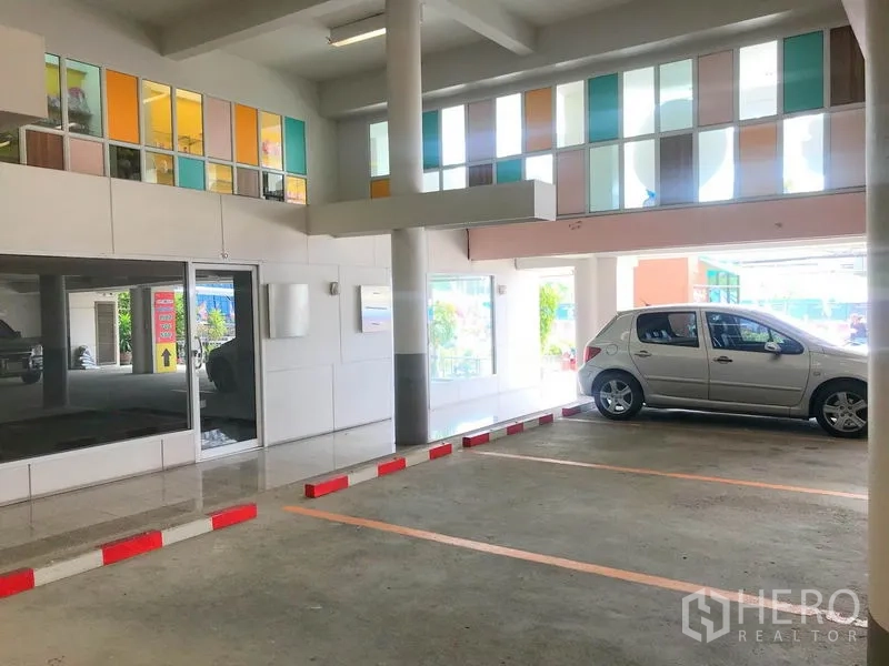 Office Space for rent in Suan Luang, Bangkok - Covered parking area with marked bays and colorful window panels inside the building.