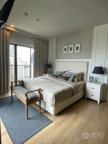 Condominium for rent in Bangkok - Spacious bedroom with upholstered headboard, bedside tables and a city-view balcony.