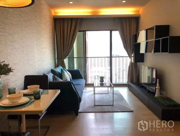 Condominium for rent in Bangkok - Bright living-dining area with floor-to-ceiling balcony doors, wall shelving, TV cabinet, and dining set.