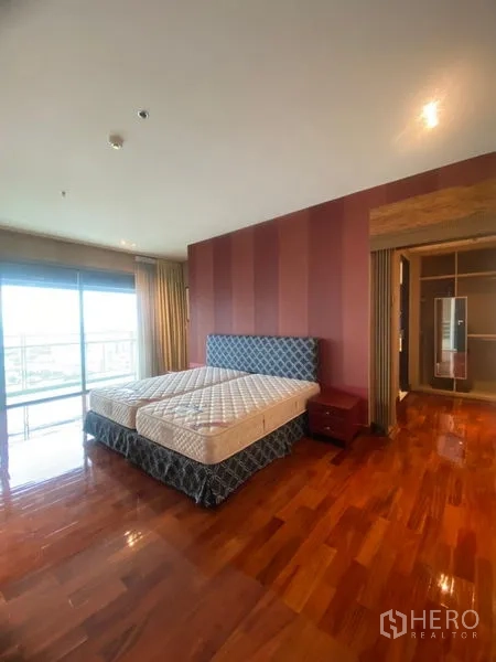 公寓 出租在Watthana, Bangkok - 主卧宽敞，实木地板、条纹背景墙，连接可赏天际线的阳台。