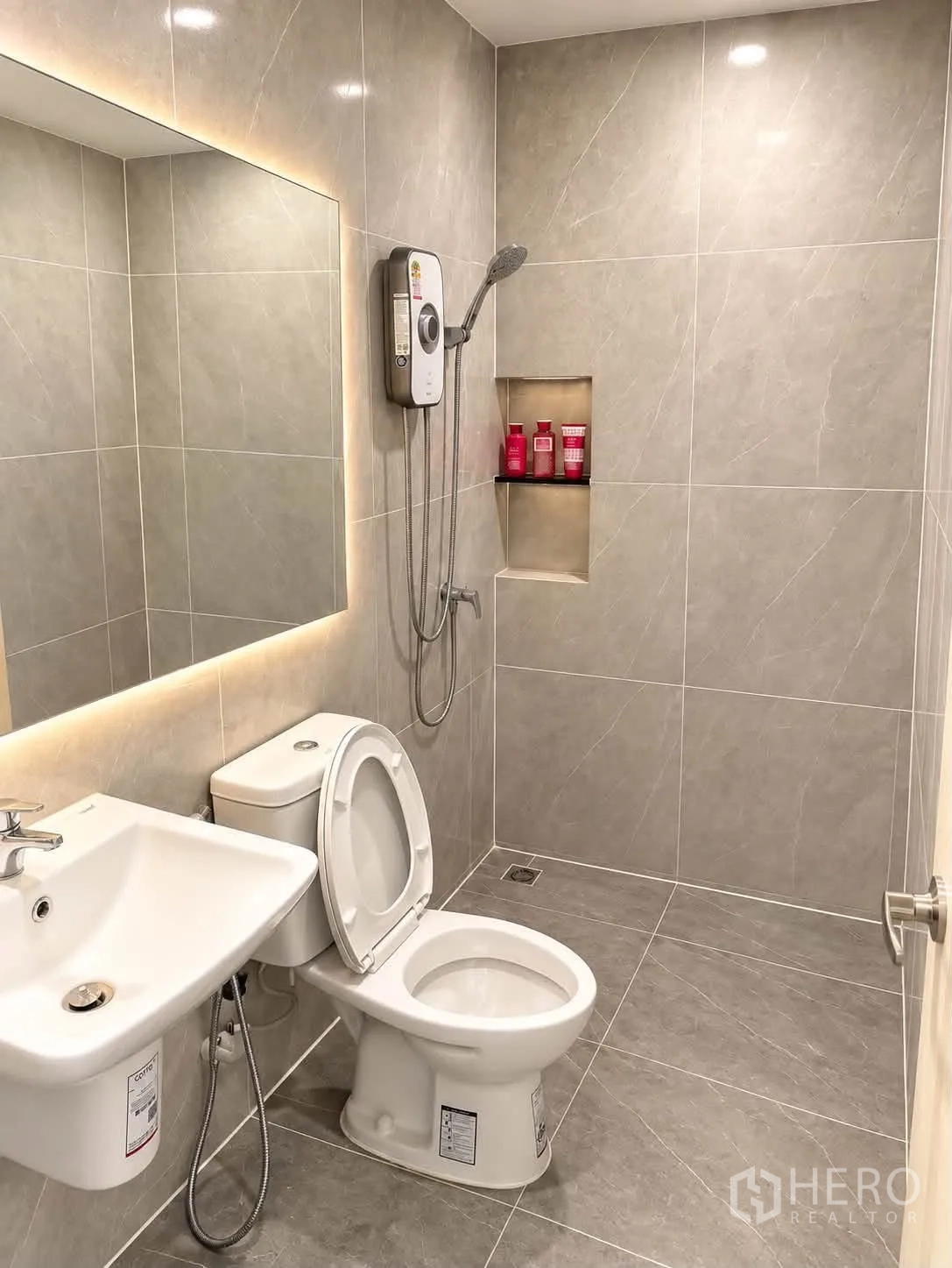 Townhouse for rent in Bang Phli, Samut Prakan - Gray-tiled bathroom with toilet, vanity, and wall-mounted water heater shower.