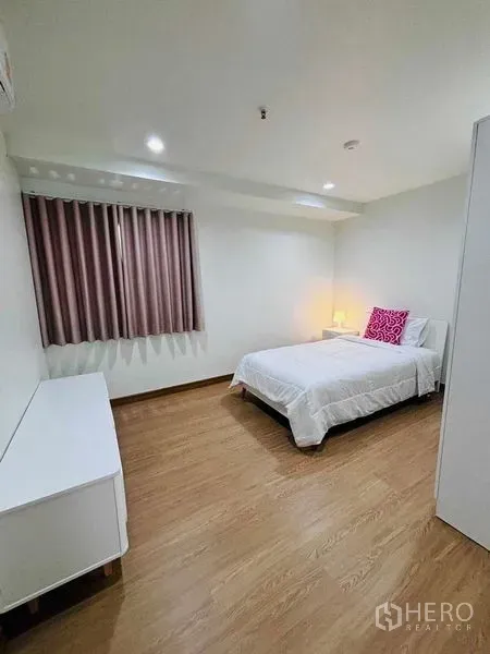 Shophouse for rent in Watthana, Bangkok - Minimalist bedroom with a single bed, bedside lamp and curtained window.
