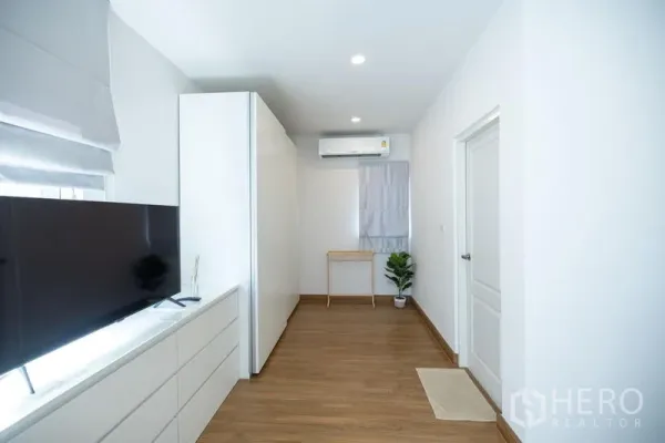 Detached House for rent or sale in Bang Phli, Samut Prakan - Long media room with TV console, white wardrobe, air conditioner and plant.