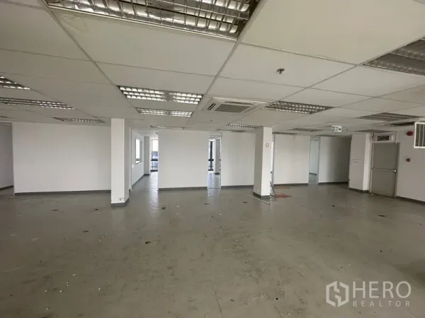 办公空间 出租在Khlong Toei, Bangkok - 空置办公内景，网格天花、荧光灯照明与多处门洞，布局灵活。