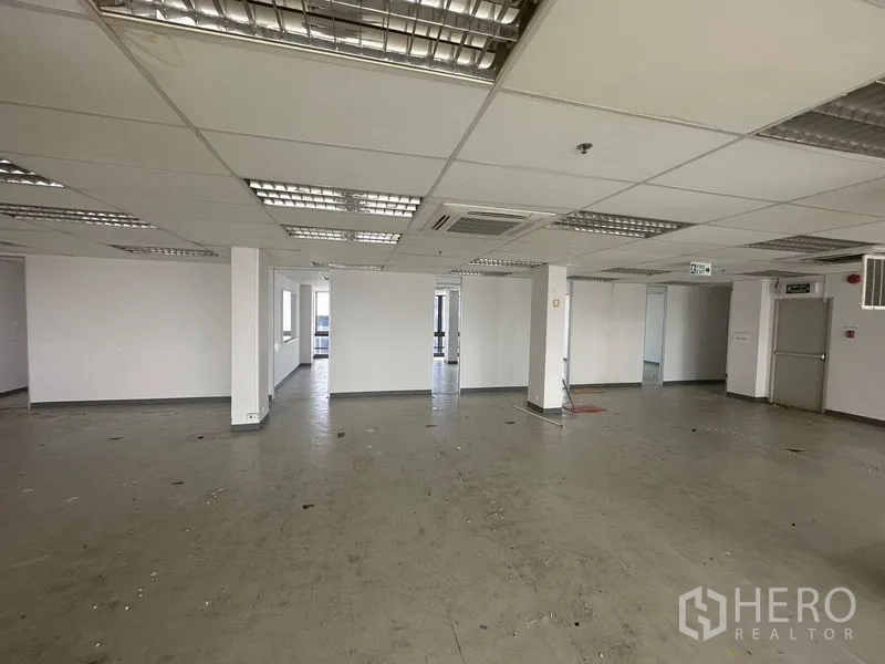 办公空间 出租在Khlong Toei, Bangkok - 空置办公内景，网格天花、荧光灯照明与多处门洞，布局灵活。