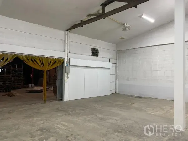 คลังสินค้า ให้เช่า - มุมโกดังแสดงทางเข้าโหลดสินค้า ม่าน PVC ตู้คอนโทรลไฟ พัดลมเพดาน และผนังกั้นสีขาว