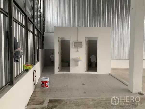 Warehouse for rent in Mueang Pathum Thani, Pathum Thani - On-site restroom block with two toilet stalls, sink and tiled floor inside the warehouse.