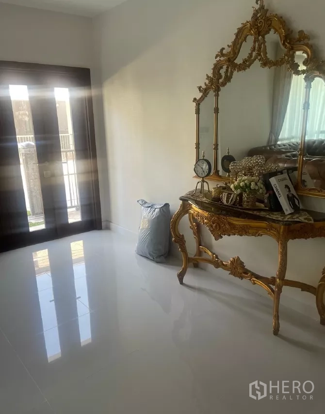 Detached House for rent or sale in Saphan Sung, Bangkok - Foyer featuring an ornate gold console table and mirror beside the front doors.