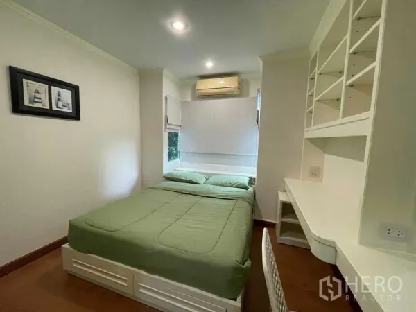 Condominium for rent - Cozy bedroom with green bedding, built-in desk and shelving with window AC.