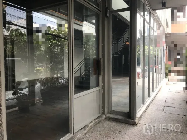 Retail Space for rent in Watthana, Bangkok - Corner entrance of the retail unit with large glass windows and door, showing an interior staircase.