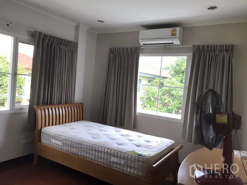 独立式住宅 出租在Phra Khanong, Bangkok - 角落卧室配单人床，多扇窗与空调机。