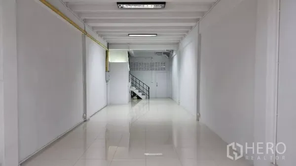 Townhouse for rent in Huai Khwang, Bangkok - Deep open-plan living area with tiled floor and a staircase at the back.