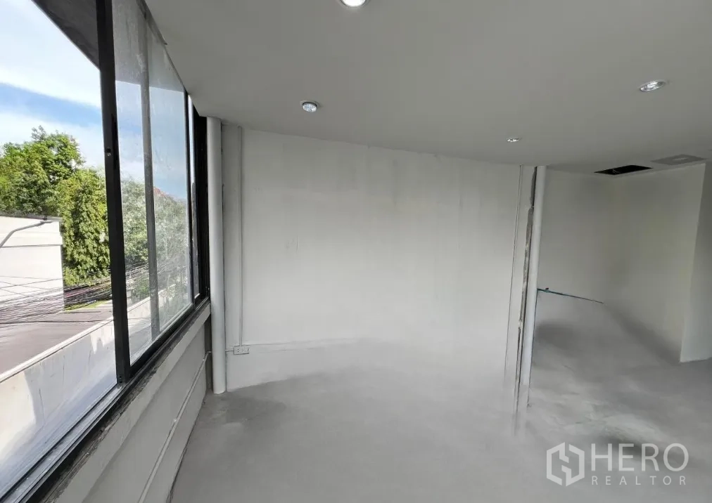 Retail Space for rent in Khlong Toei, Bangkok - Open white-walled retail space with corner windows and recessed ceiling lights.