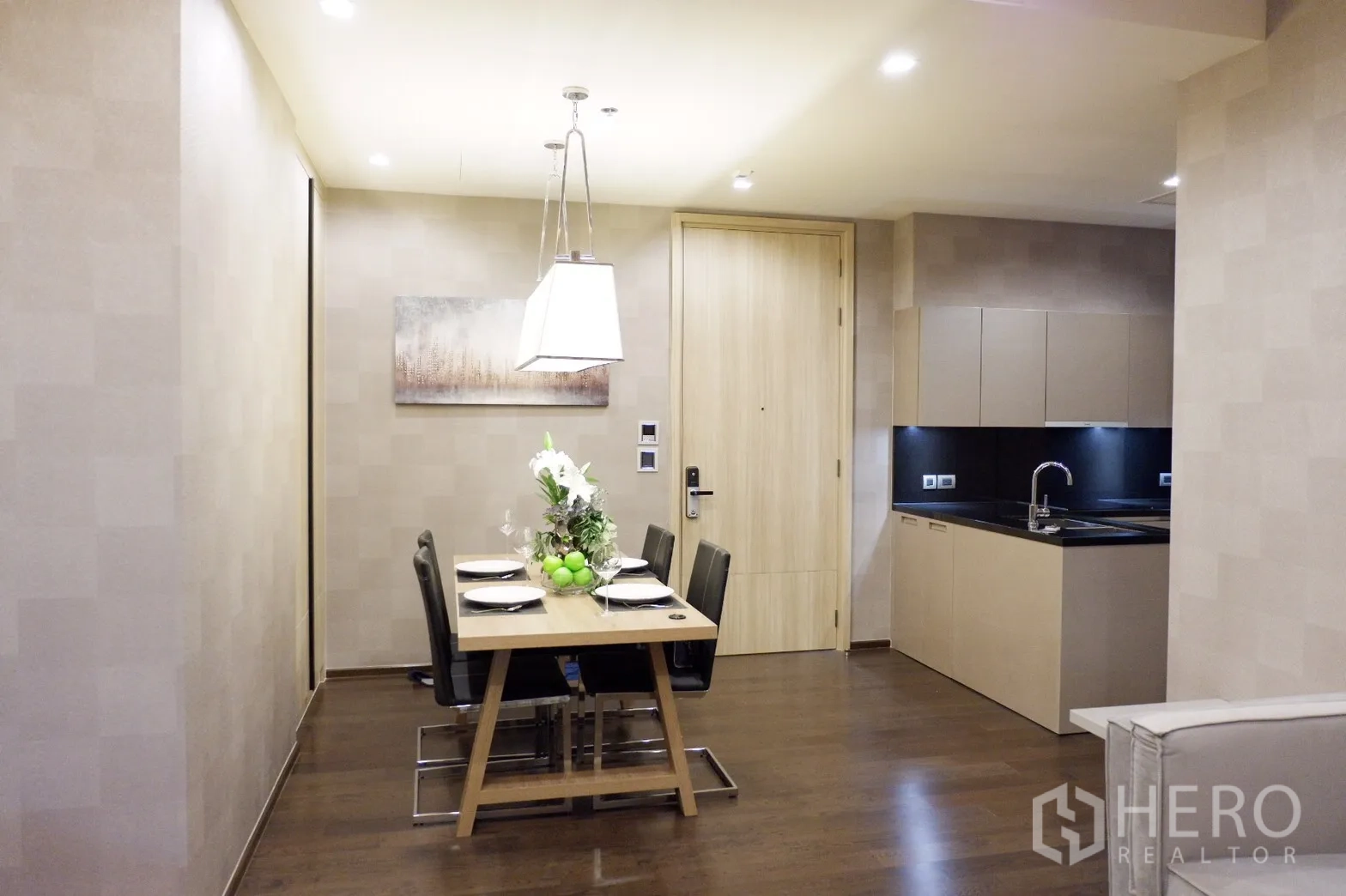 Condominium for rent in Watthana, Bangkok - Open-plan dining area beside a sleek kitchen, table set for four under a pendant light.