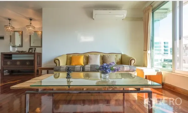 Condominium for rent in Pathum Wan, Bangkok - Sunlit living room with vintage sofa, glass coffee table and warm wood floors.