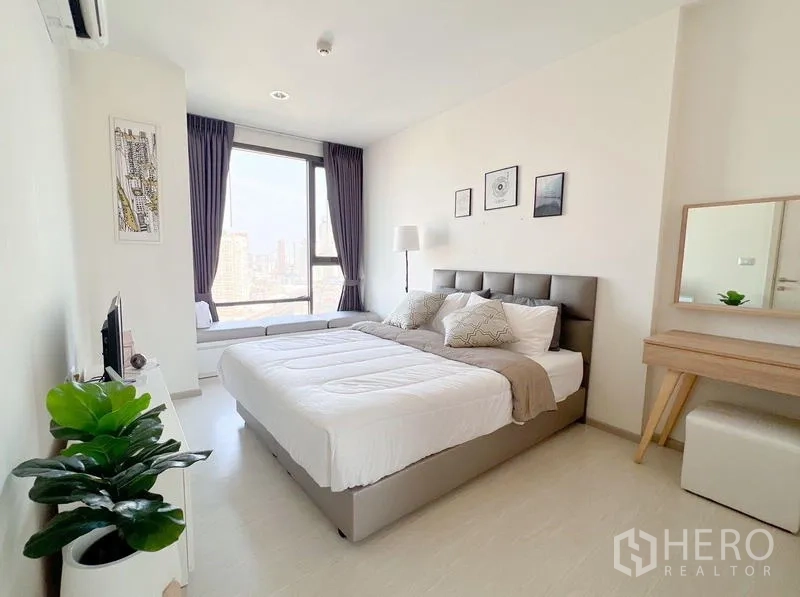Condominium for rent or sale in Khlong Toei, Bangkok - Spacious bedroom with window bench, floor lamp and indoor plant.