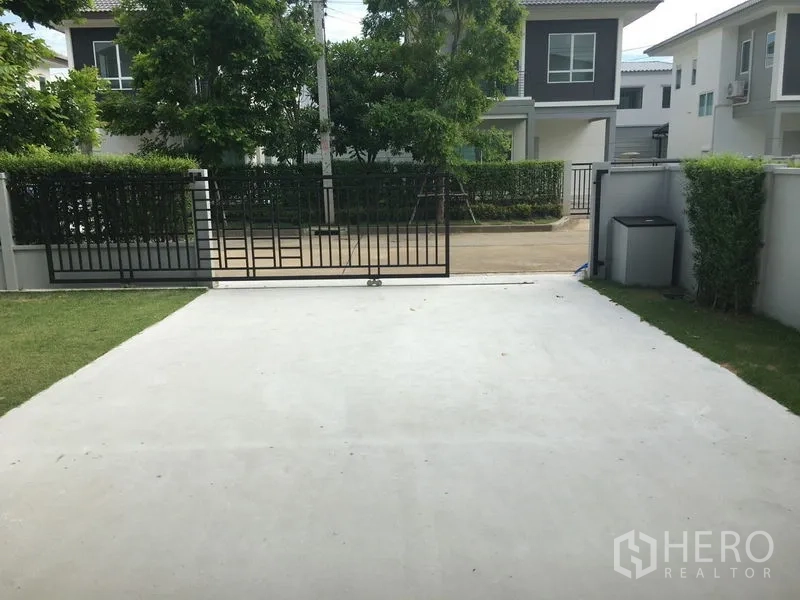 Detached House for rent in Khlong Luang, Pathum Thani - View from carport toward the front gate and quiet neighborhood road.