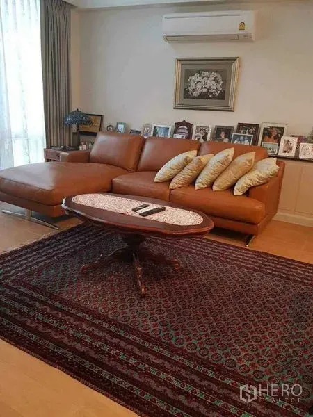 Townhouse for sale in Yan Nawa, Bangkok - Bright lounge with leather sectional sofa, large curtained window and classic coffee table.