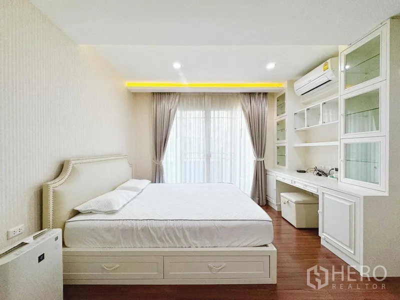 Townhouse for rent in Phra Khanong, Bangkok - King-size bedroom with storage bed and sheer drapes to the balcony.