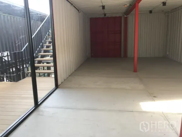 办公空间 出租在Khlong Toei, Bangkok - 开放式集装箱风格办公室，落地玻璃配露台与外楼梯，水泥地面与红色钢梁。