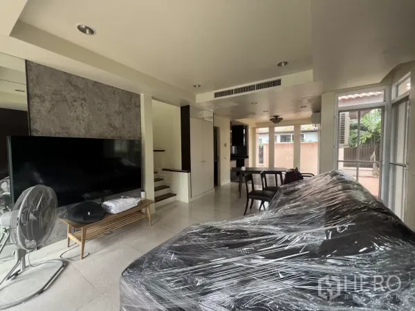 Detached House for rent in Wang Thonglang, Bangkok - Living room view toward dining area and staircase with floor-to-ceiling windows.