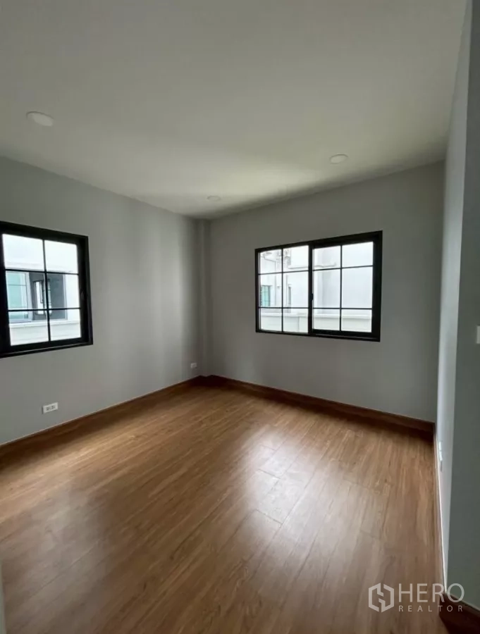 Detached House for rent in Bang Phli, Samut Prakan - Secondary bedroom with two windows and wood floors.