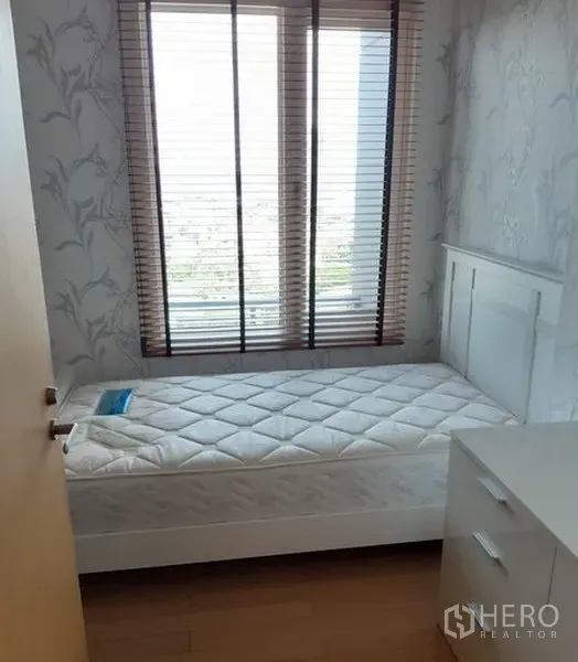 Condominium for rent in Khlong Toei, Bangkok - Cozy single bedroom with large window, blinds, white furniture and wood flooring.