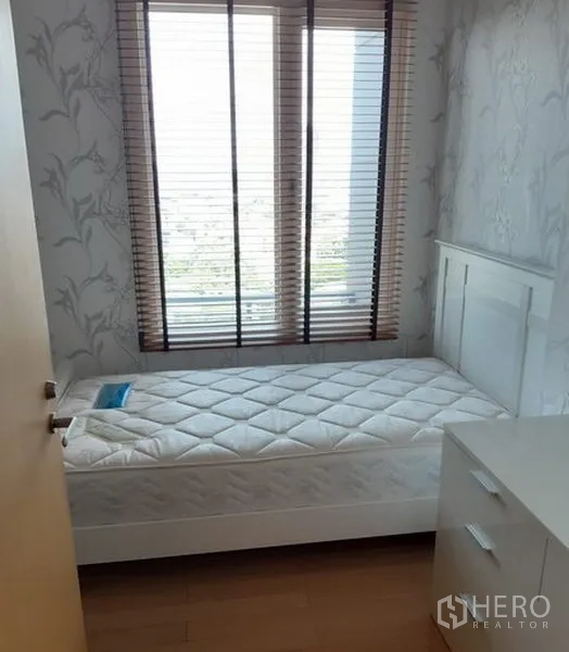 Condominium for rent in Khlong Toei, Bangkok - Cozy single bedroom with large window, blinds, white furniture and wood flooring.