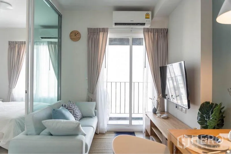 คอนโด ขายในHuai Khwang, Bangkok - โซนนั่งเล่นโทนพาสเทล ทีวีติดผนัง และประตูกระจกออกไประเบียง