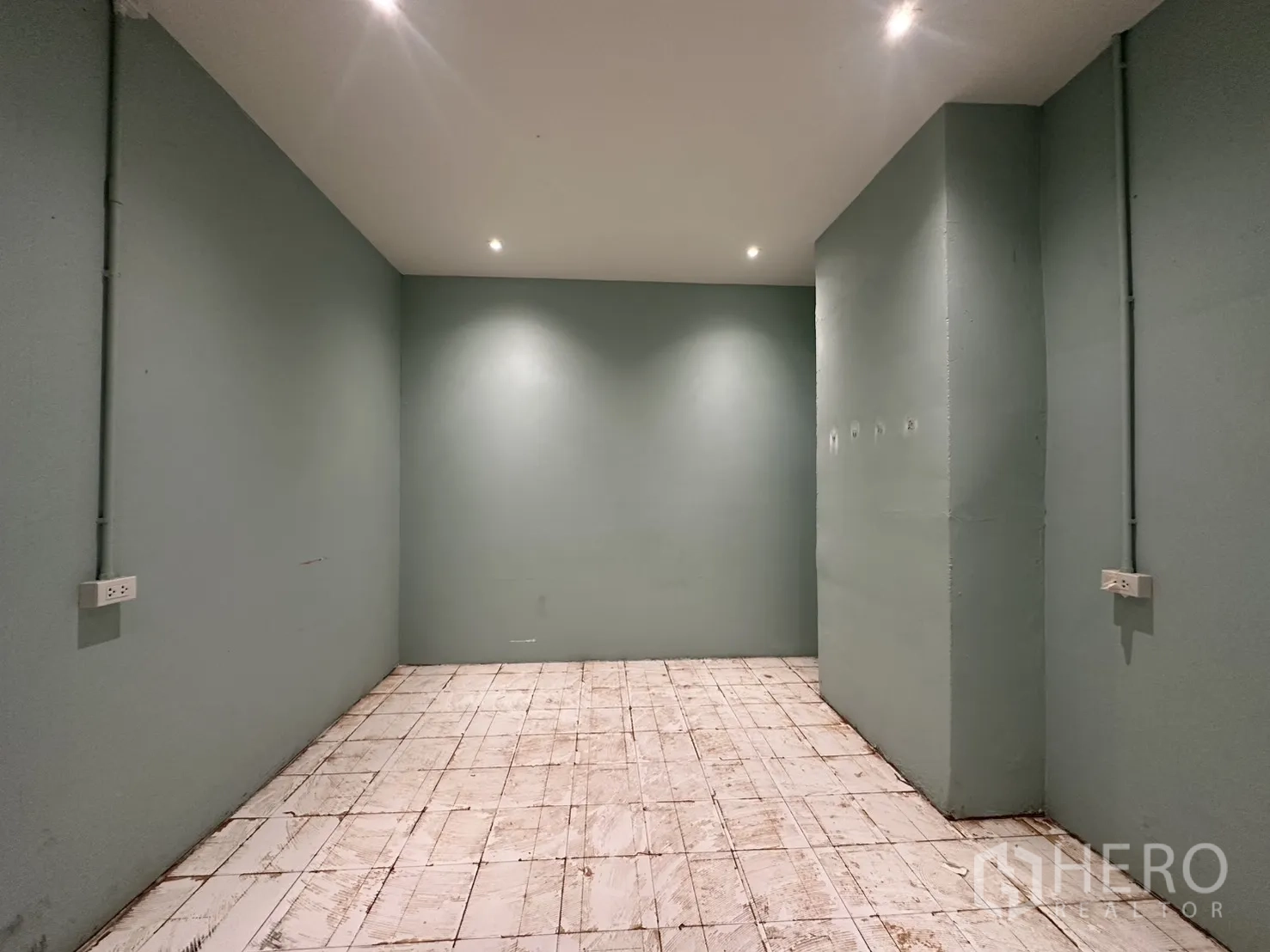 零售空间 for rent in Watthana, Bangkok - 狭长房间，绿色墙面、瓷砖地面、天花射灯与墙面电源插座。