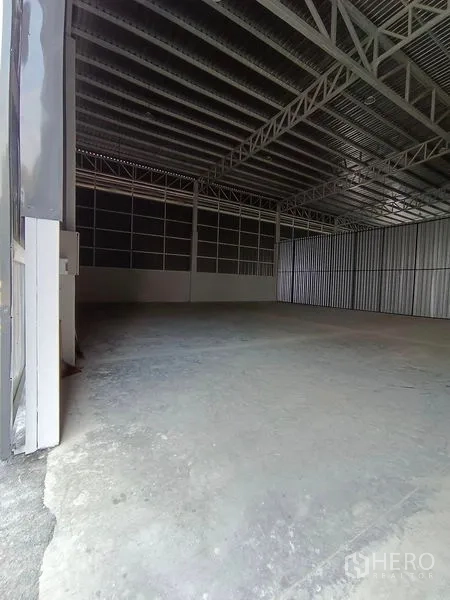 Warehouse for rent in Khlong Toei, Bangkok - View from the large entry into an empty warehouse bay with steel truss ceiling and concrete slab.