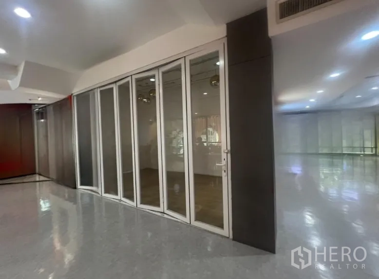 Retail Space for rent in Pathum Wan, Bangkok - Corner 31 sqm retail unit with folding glass storefront beside a polished indoor corridor in Pathum Wan, Bangkok.