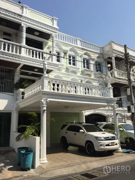 Home Office for rent or sale in Watthana, Bangkok - Three-storey home office facade with white balustrades, covered carport and a parked SUV.