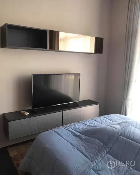 Condominium for rent or sale in Watthana, Bangkok - Cozy bedroom with TV console, wall cabinets and floor-to-ceiling curtains.