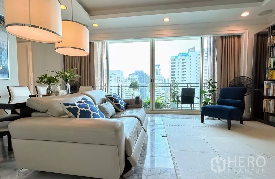 Condominium for sale in Watthana, Bangkok - Cozy living area with cream sofa, large lamps and balcony plants overlooking Bangkok city.