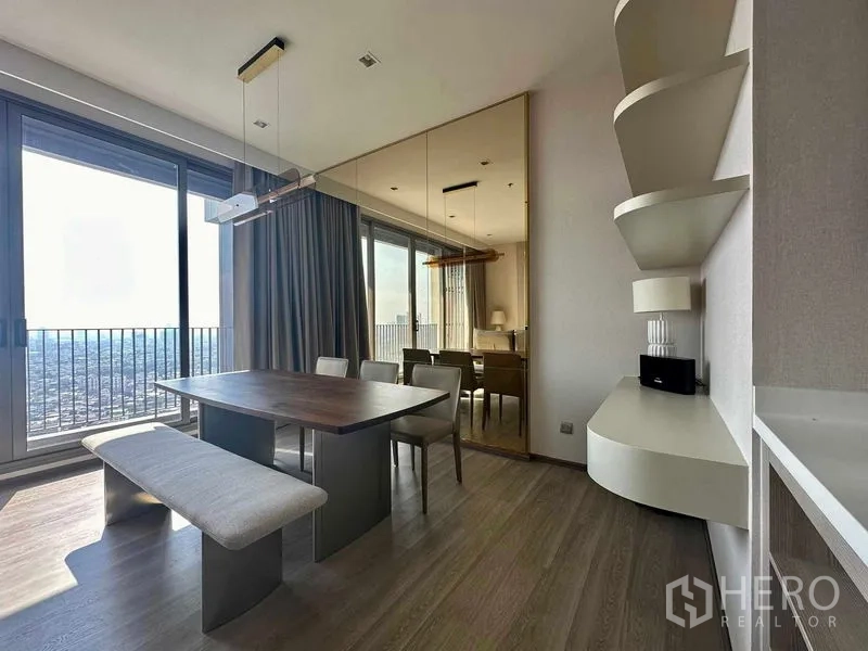 Condominium for rent in Bang Kho Laem, Bangkok - Dining area with bench seating beside sliding glass doors to the balcony and a mirrored feature wall.