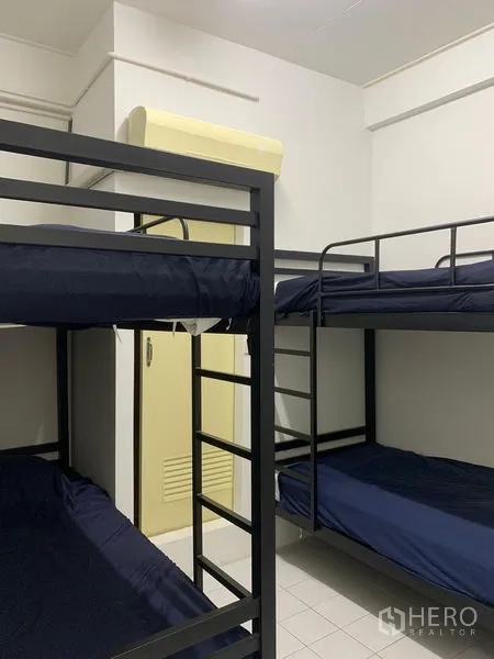 Shophouse for rent in Khlong Toei, Bangkok - Dorm room with navy bedding on metal bunk beds and a wall-mounted air conditioner.