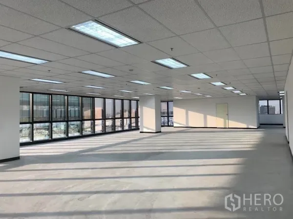 Office Space for rent in Din Daeng, Bangkok - Spacious corner office space with wraparound windows, structural columns, and fluorescent lighting.