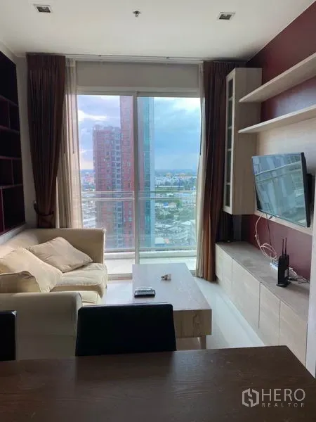 公寓 出租在Watthana, Bangkok - 客厅带沙发、电视与壁柜，落地窗连通阳台，眺望城市景观
