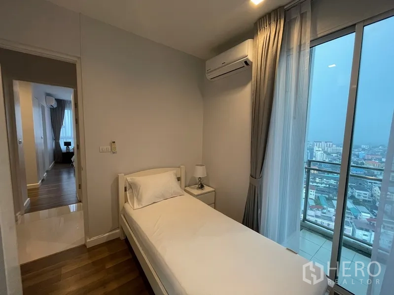 คอนโด ให้เช่าหรือขายในWatthana, Bangkok - ห้องนอนขนาดกะทัดรัด เตียงเดี่ยว แอร์ และประตูกระจกสไลด์ออกระเบียง มองเห็นวิวเมืองกรุงเทพฯ