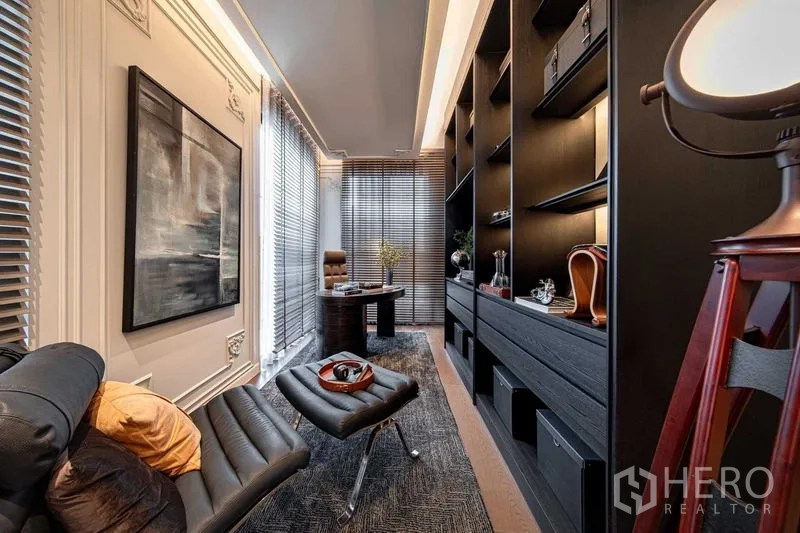 Detached House for sale in Saphan Sung, Bangkok - Modern home office with leather lounge chair, built-in black bookshelves and desk beside tall windows.